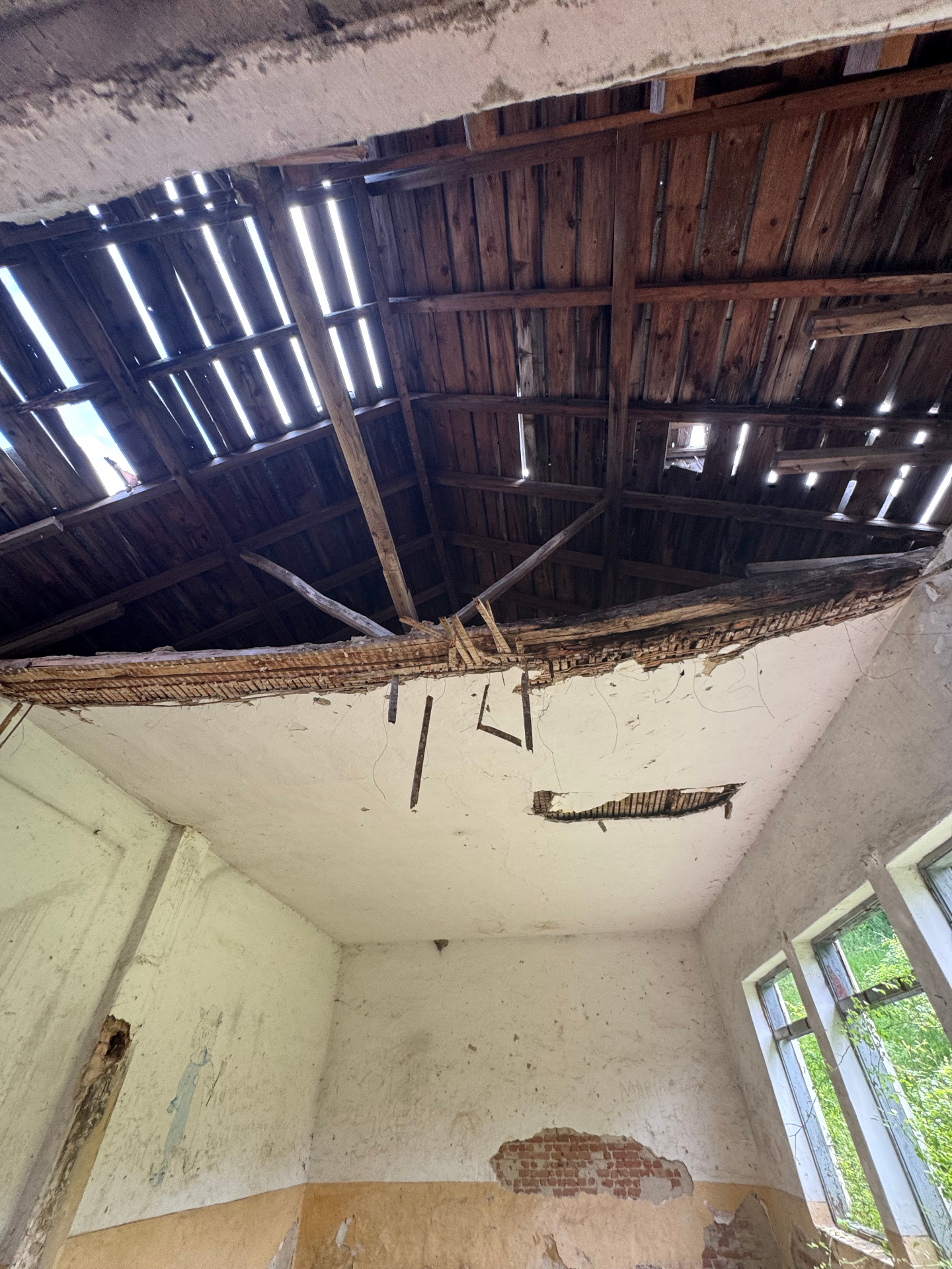 Collapsed roof and exposed wooden beams inside the abandoned building