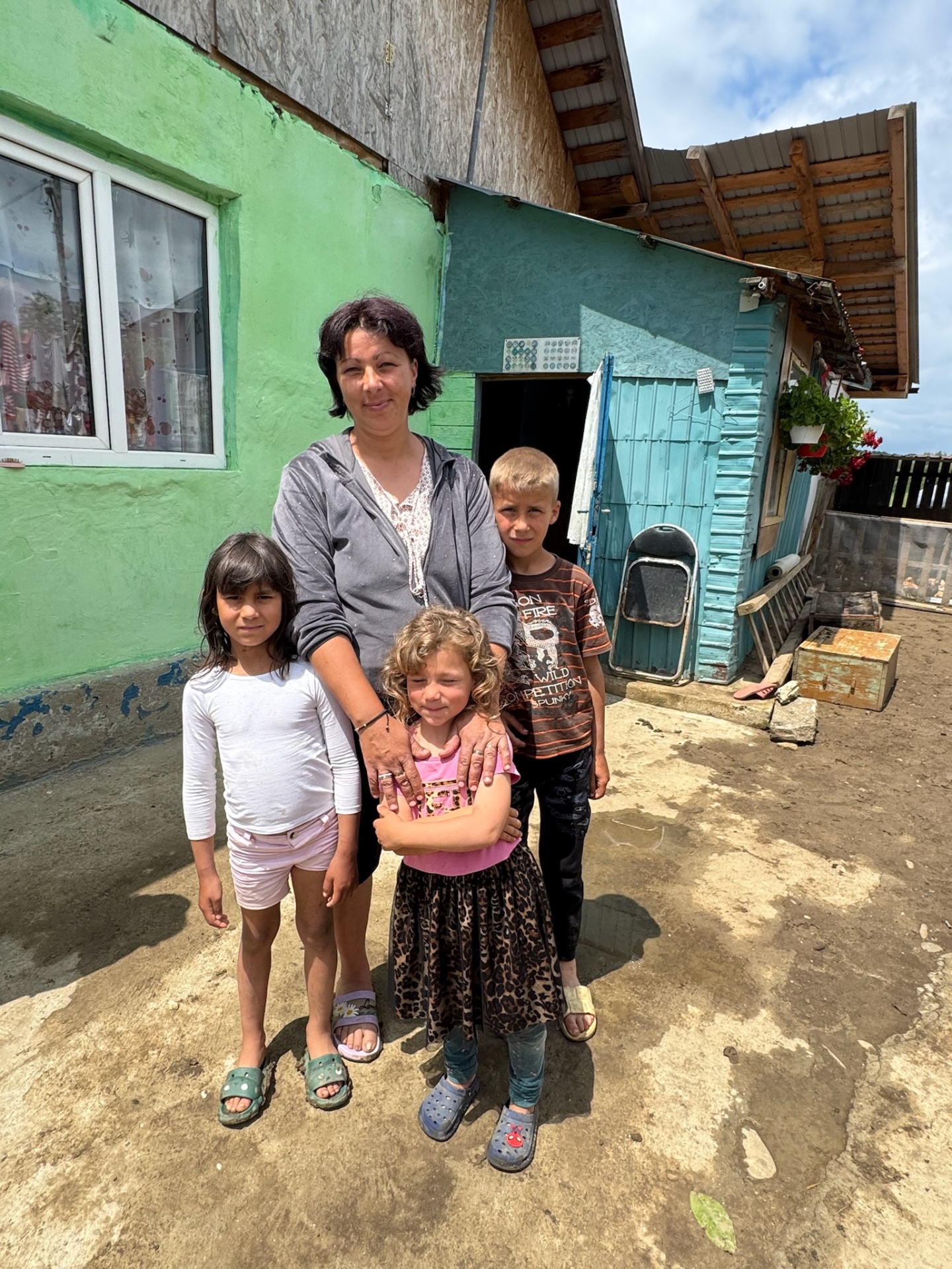 A widowed mother with her children outside their home in Păcureți