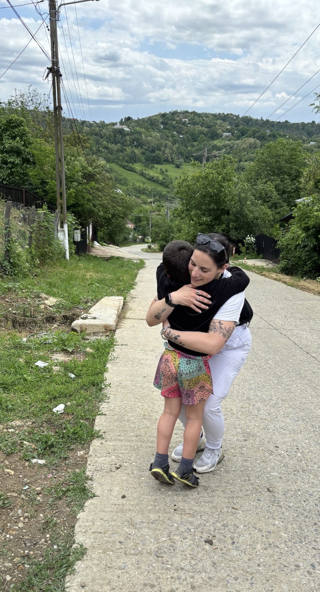 A volunteer hugging a child on a village road in Păcureți